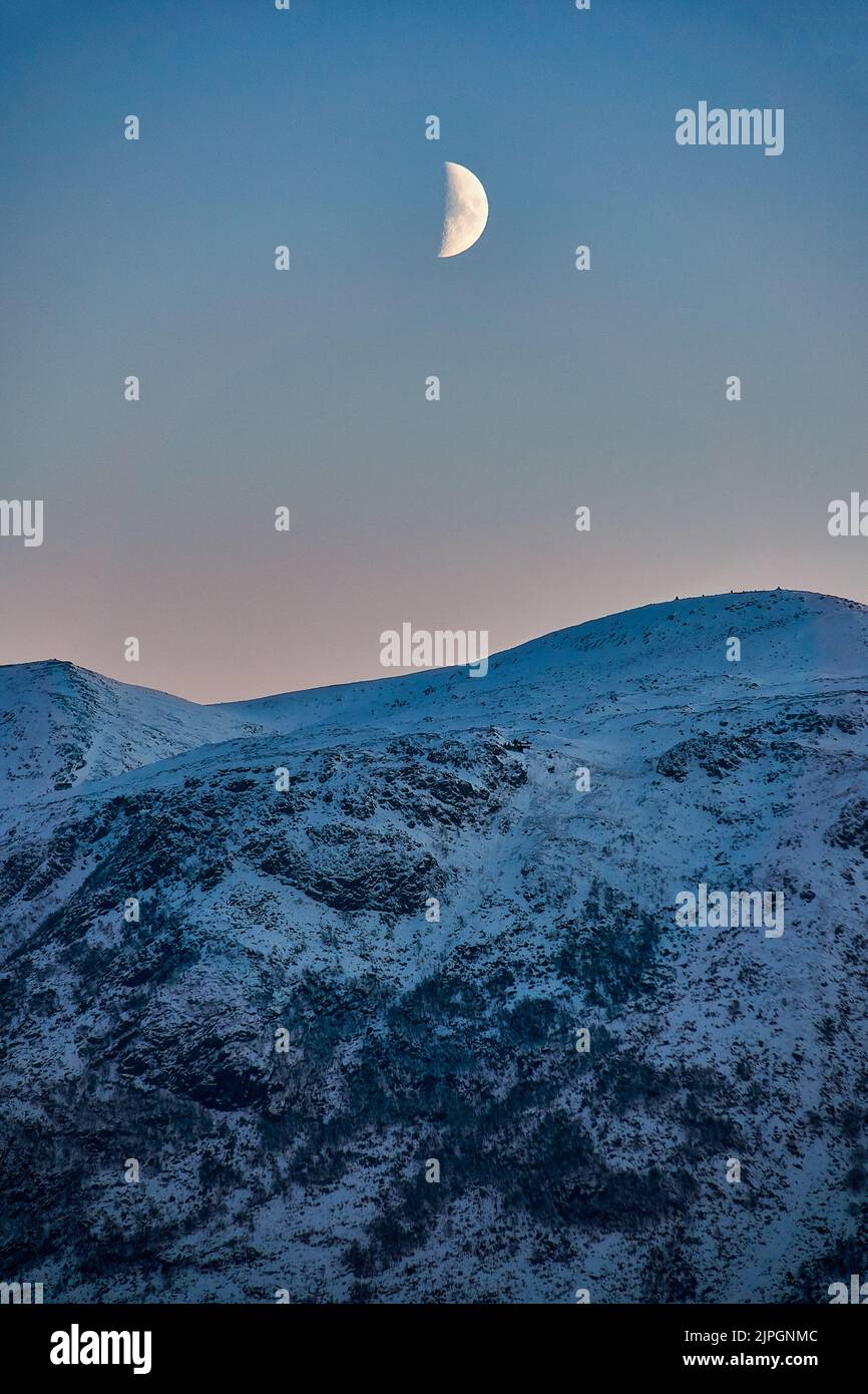 Luna che sorge sopra la montagna su Godøy in inverno, Sunnmøre, Møre og Romsdal, Norvegia. Foto Stock