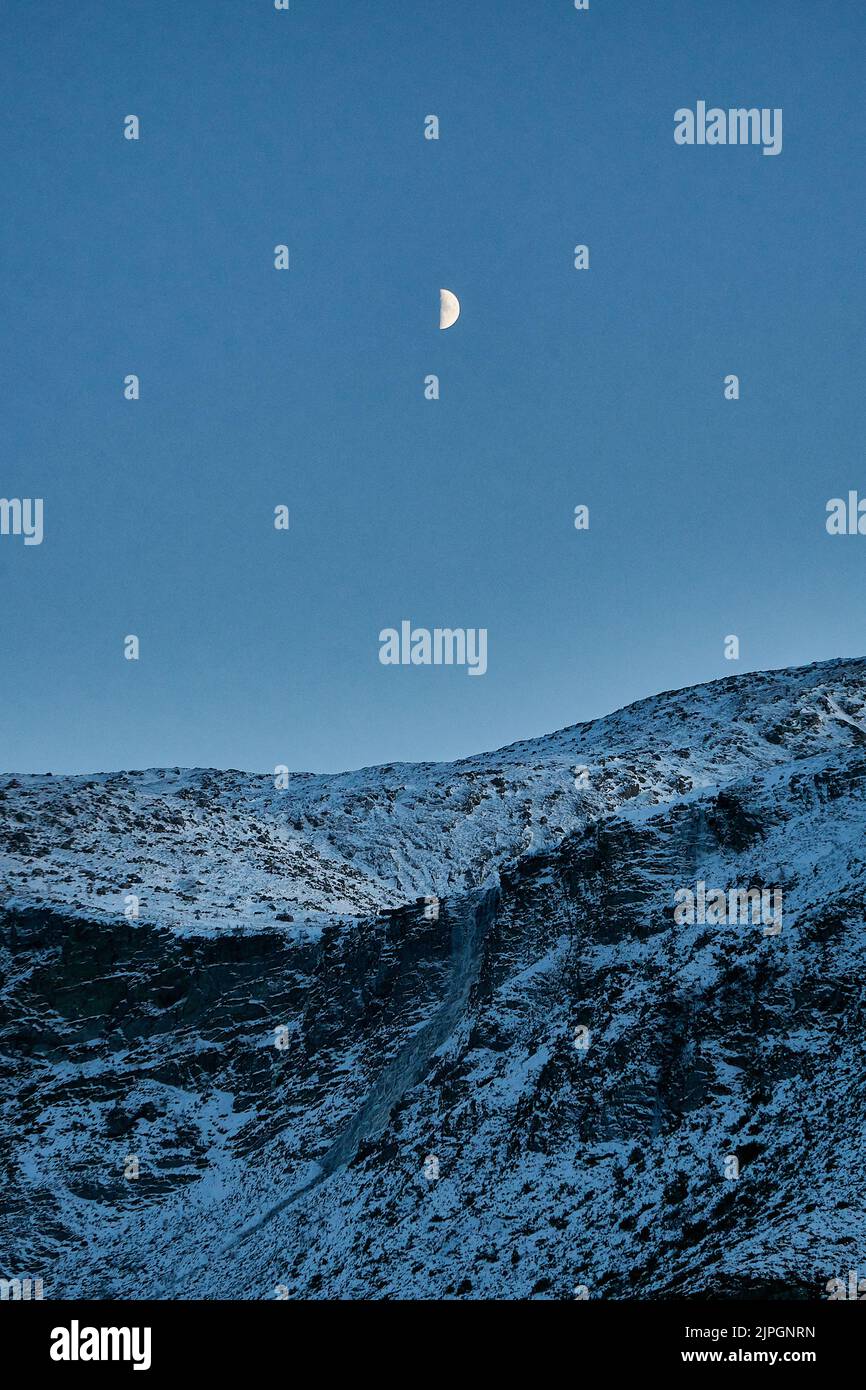 Luna che sorge sopra la montagna su Godøy in inverno, Sunnmøre, Møre og Romsdal, Norvegia. Foto Stock