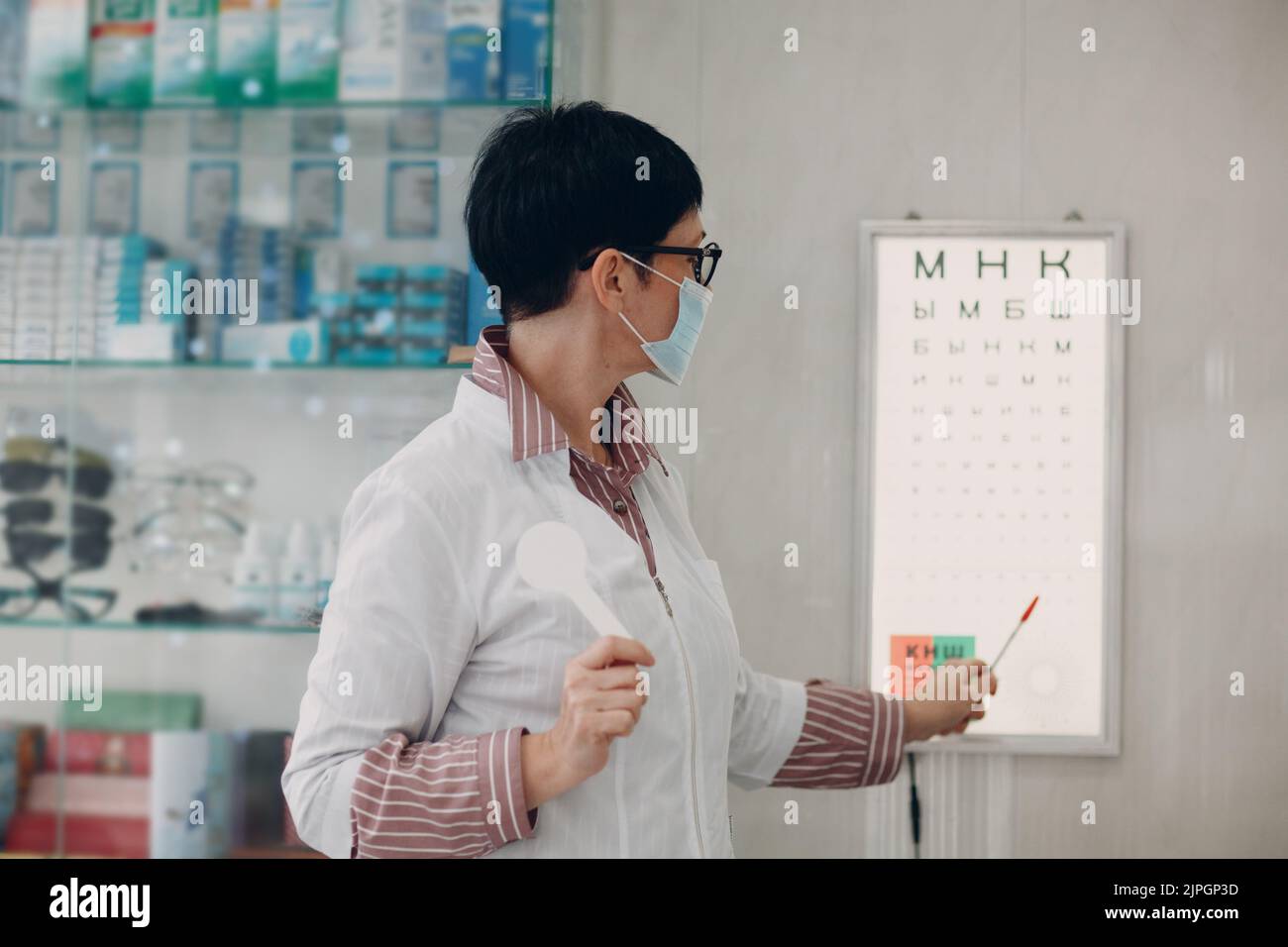 Medico ottico con grafico a lettere per il controllo del test di visione oculare. Foto Stock
