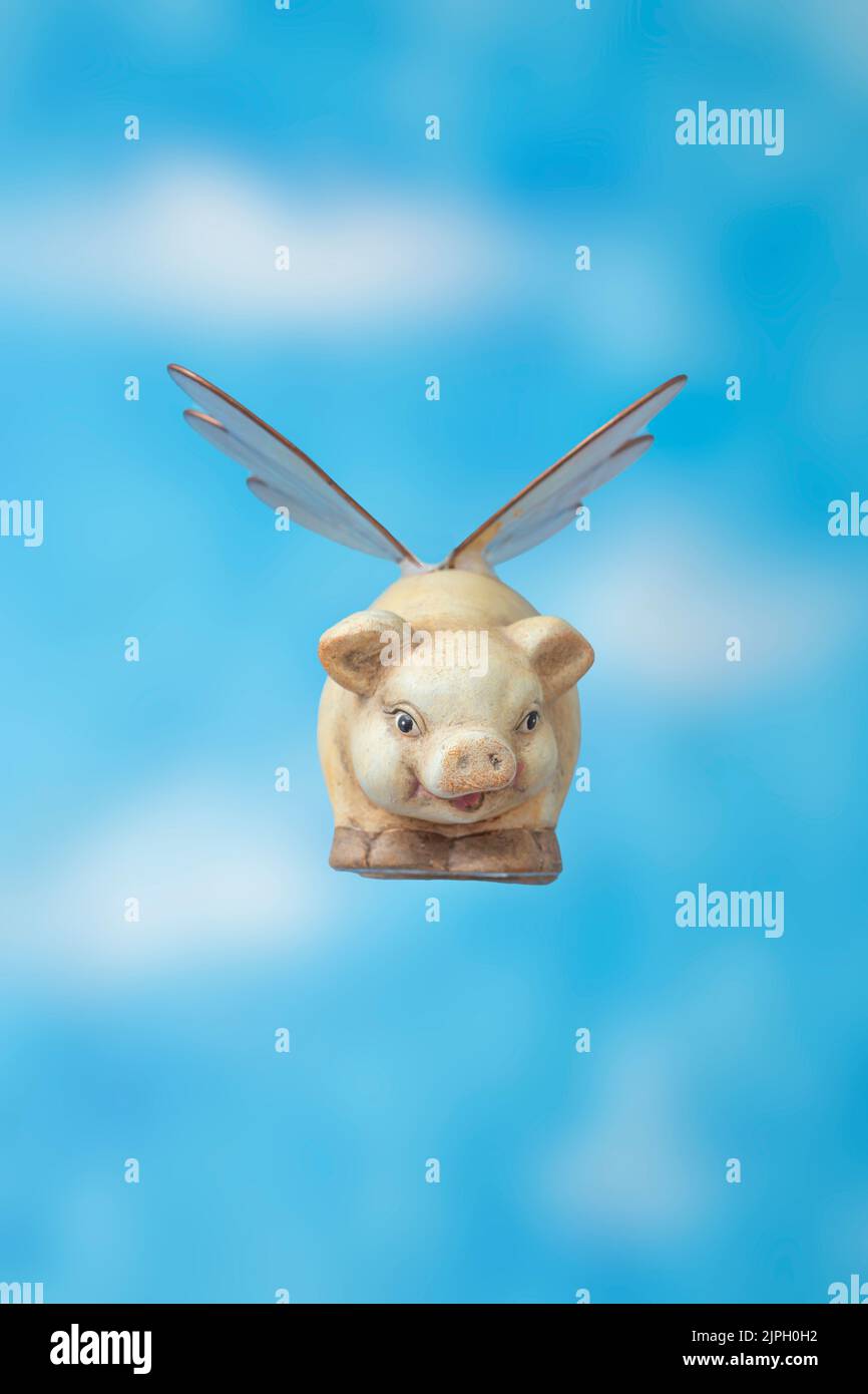 Ceramico Piggy bank con ali di insetto che volano su sfondo blu skyes, vista frontale. Quando i maiali volano metafora. Foto Stock