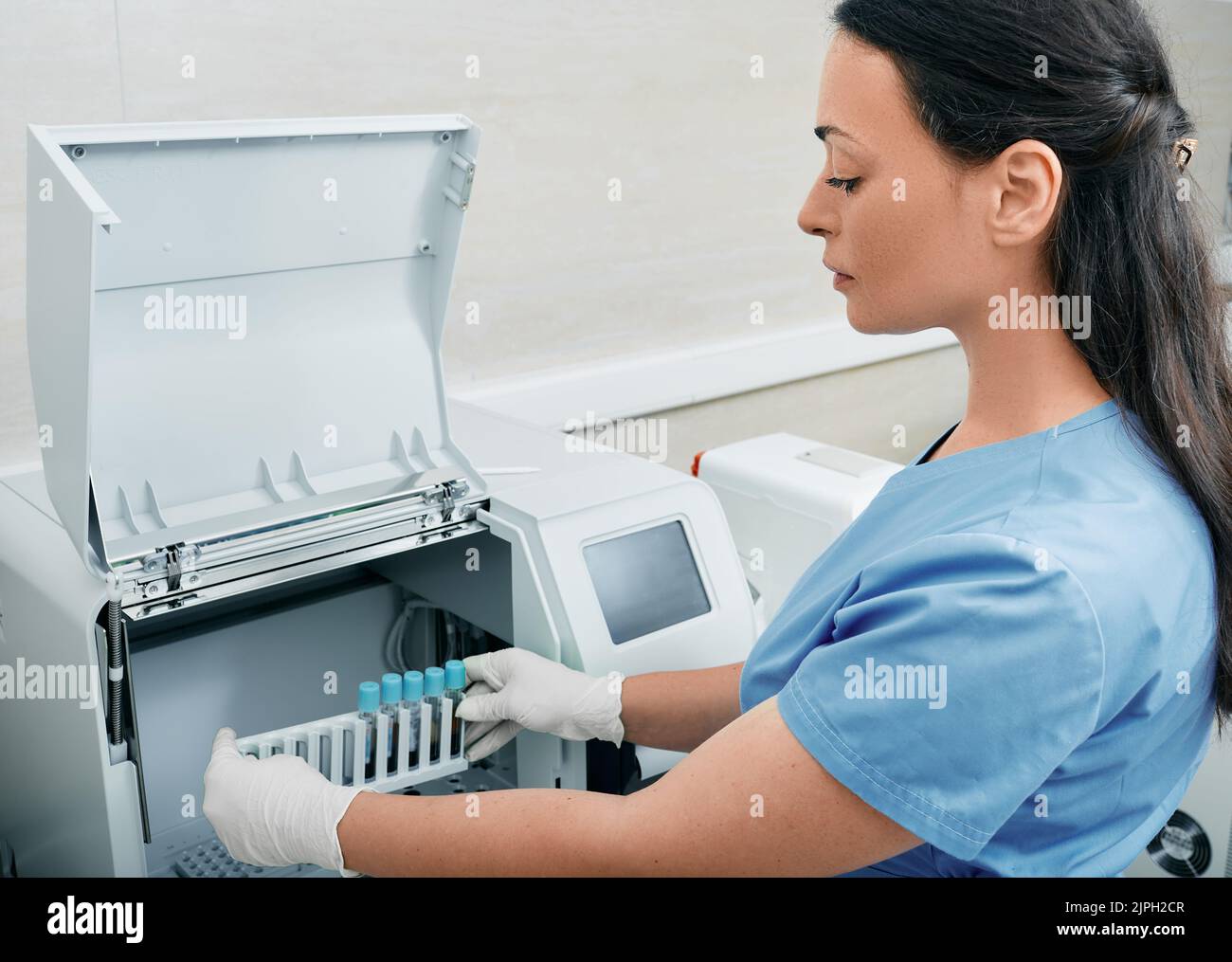 Analisi della coagulazione dei campioni di sangue. Tecnico di laboratorio femminile che carica i campioni di sangue per l'analisi dei test di coagulazione presso il laboratorio di ricerca medica Foto Stock