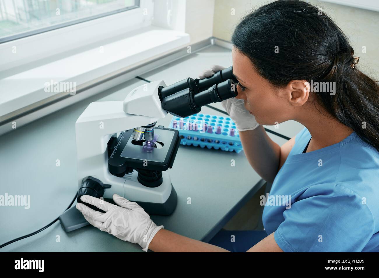 Assistente di laboratorio ricerca e ricerca di campione di prova sotto microscopio medico in laboratorio scientifico. laboratorio medico Foto Stock