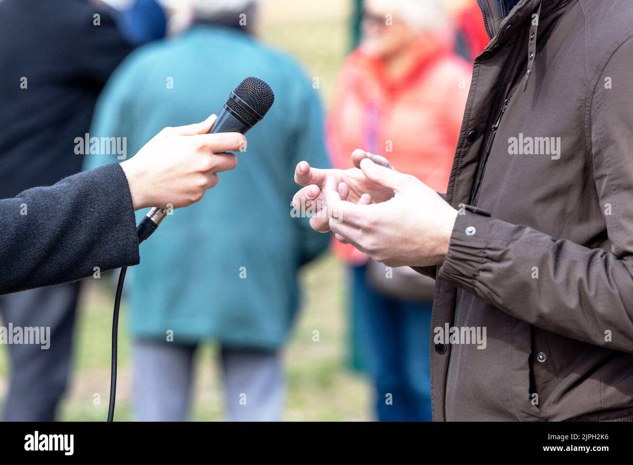 Giornalista che fa media o vox pop intervista con una persona irriconoscibile Foto Stock