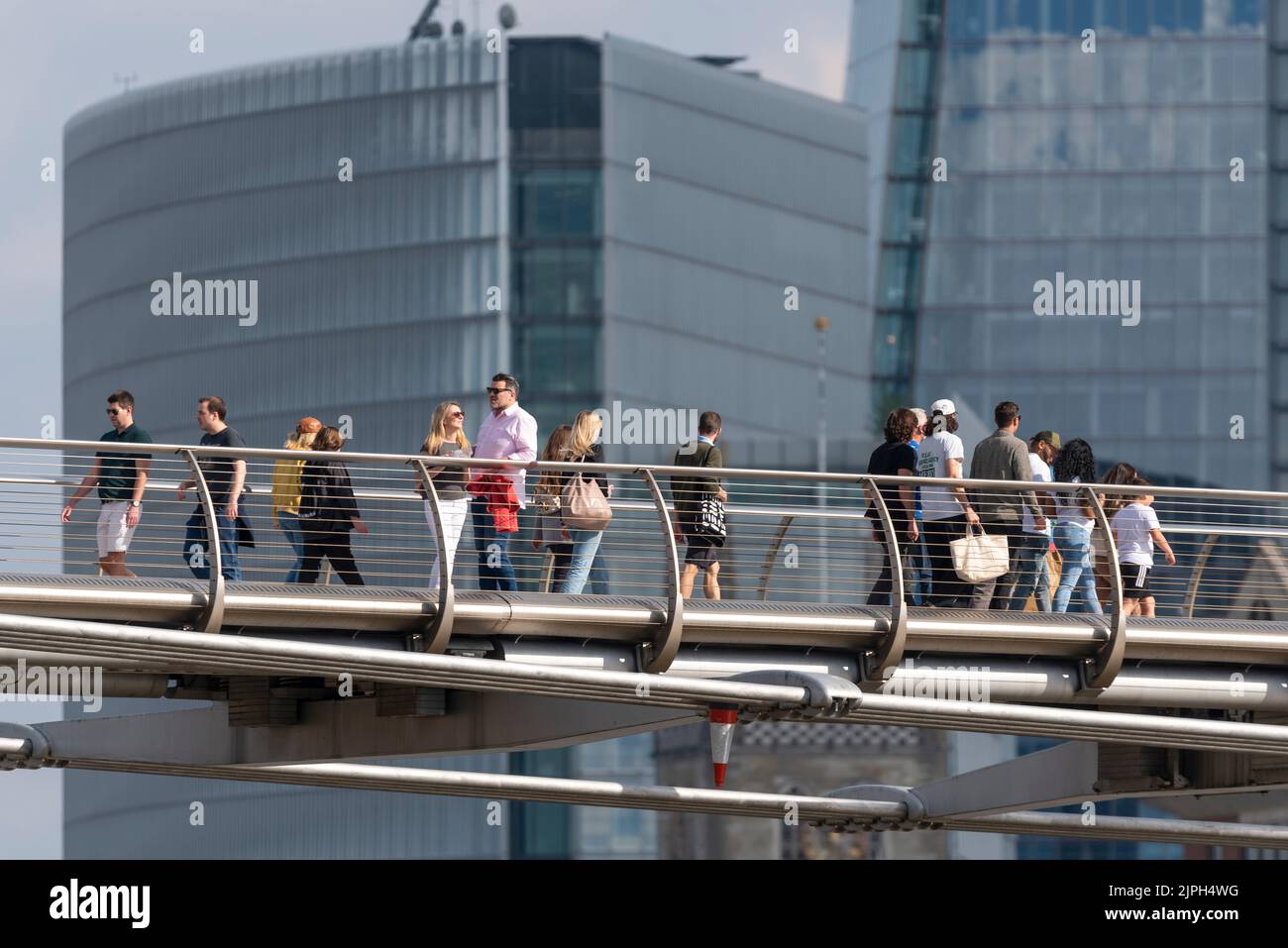 Persone che camminano attraverso il Millennium Bridge sopra il Tamigi, Londra, Regno Unito, di fronte ad alti sviluppi. Una pausa di un paio per chattare Foto Stock