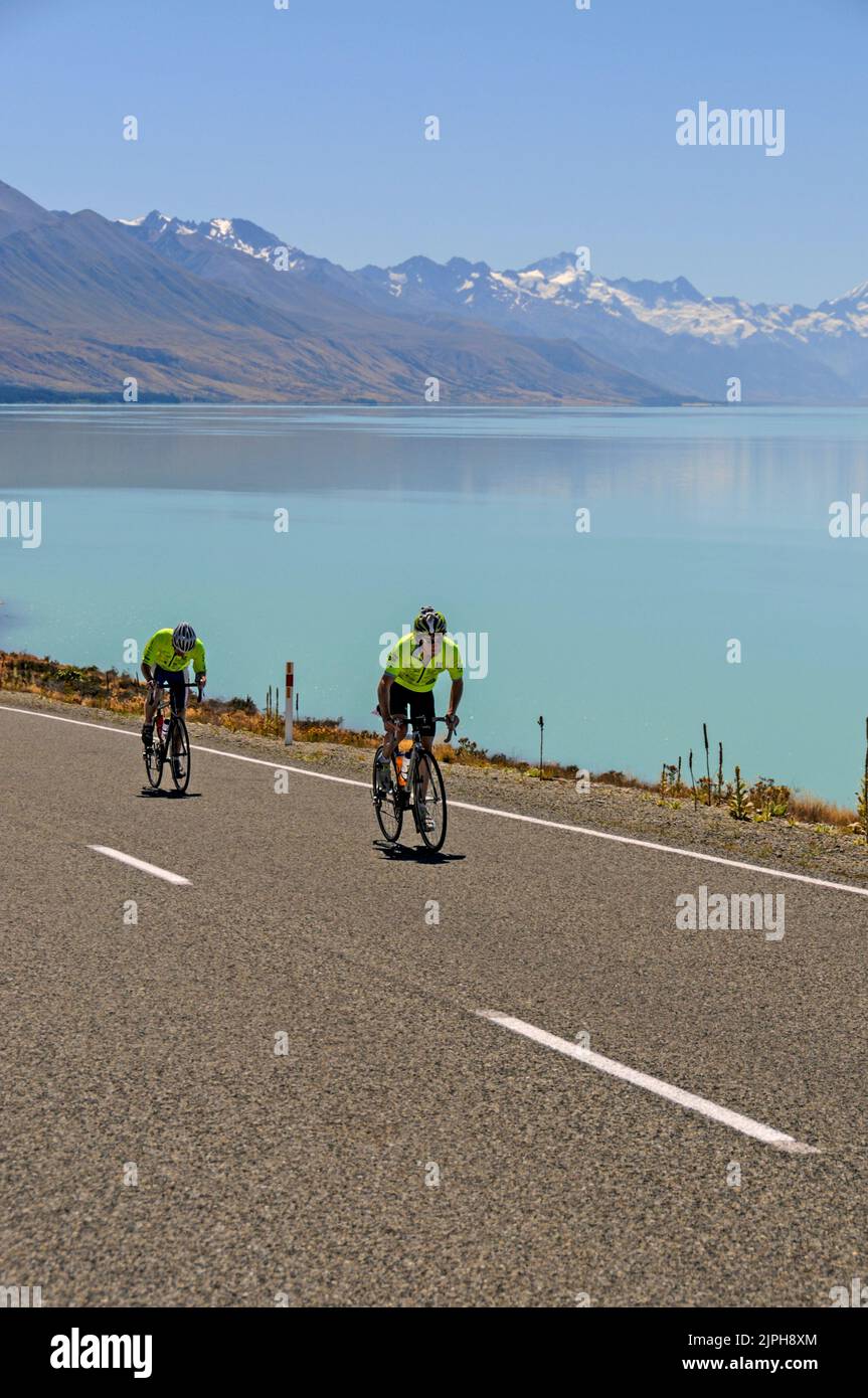 Una corsa ciclistica in aiuto di beneficenza sull'autostrada statale 8 corre lungo la riva del lago Tekapo nella regione di Mackenzie, South Island, in Nuova Zelanda. In lontananza Foto Stock