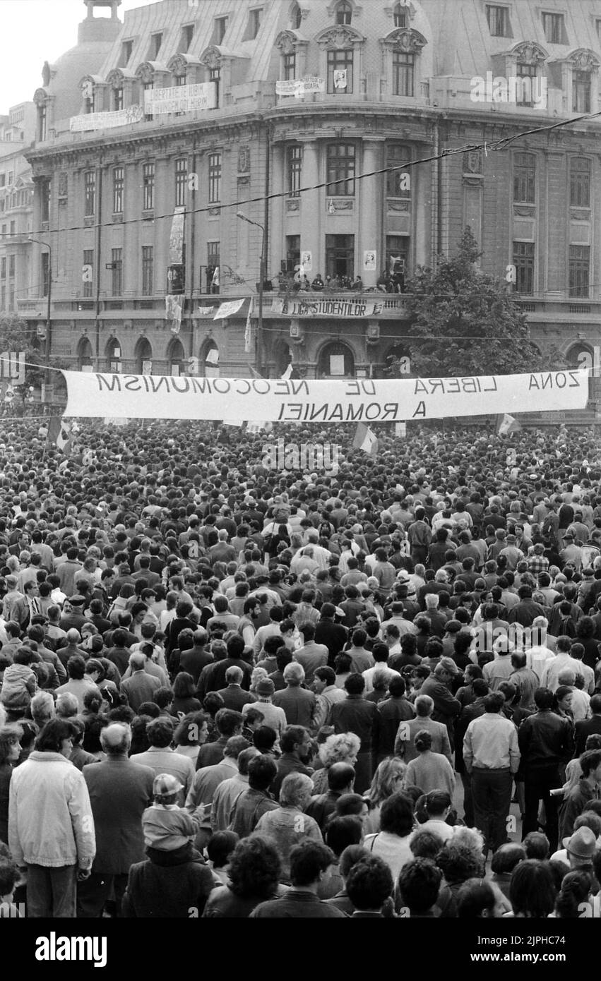Bucarest, Romania, aprile 1990. 'Golaniada', una grande protesta anti-comunismo in Piazza dell'Università dopo la Rivoluzione rumena del 1989. La gente si riunirebbe ogni giorno per protestare contro gli ex comunisti che hanno preso il potere dopo la Rivoluzione. Il balcone dell'edificio dell'Università divenne "la piattaforma per la democrazia", un tempo usato per rivolgersi alla folla. Il banner dice "la zona franca neomunistica della Romania”. Foto Stock
