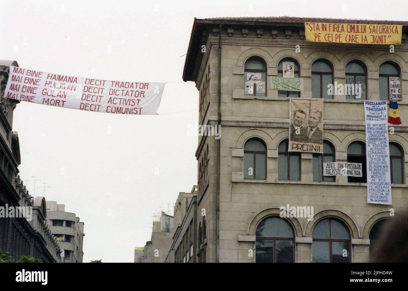Bucarest, Romania, aprile 1990. 'Golaniada', una grande protesta anti-comunismo in Piazza dell'Università dopo la Rivoluzione rumena del 1989. La gente si riunirebbe ogni giorno per protestare contro gli ex comunisti che hanno preso il potere dopo la Rivoluzione. Vari striscioni sono appesi alle pareti dell'edificio universitario. Uno di loro mostra il dittatore Ceausescu e il presidente Iliescu con la spiegazione 'amici'. Foto Stock