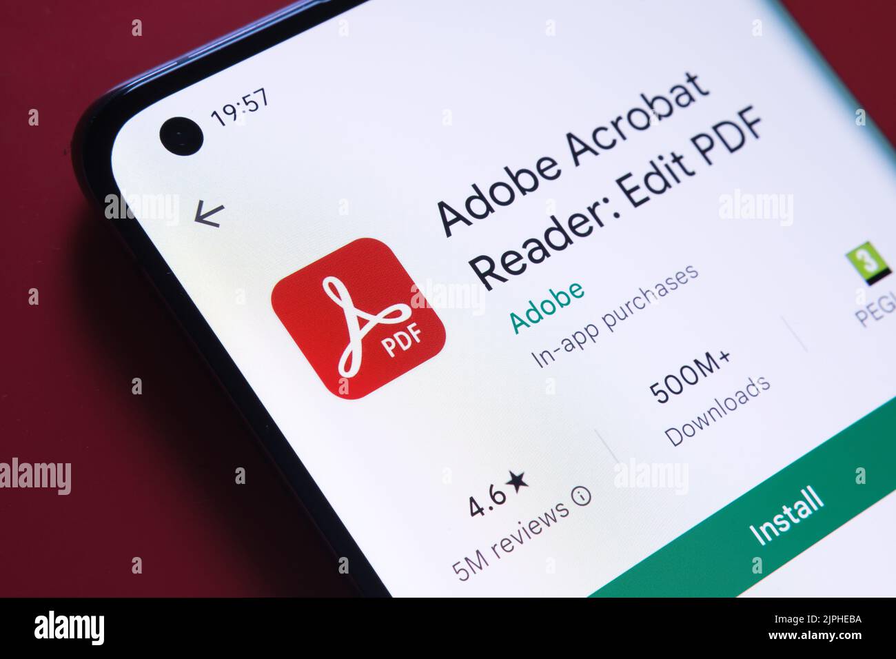 App adobe acrobat PDF visualizzata in Google Play Store sullo schermo dello smartphone su sfondo rosso. Foto ravvicinata con messa a fuoco selettiva. Stafford, unità Foto Stock