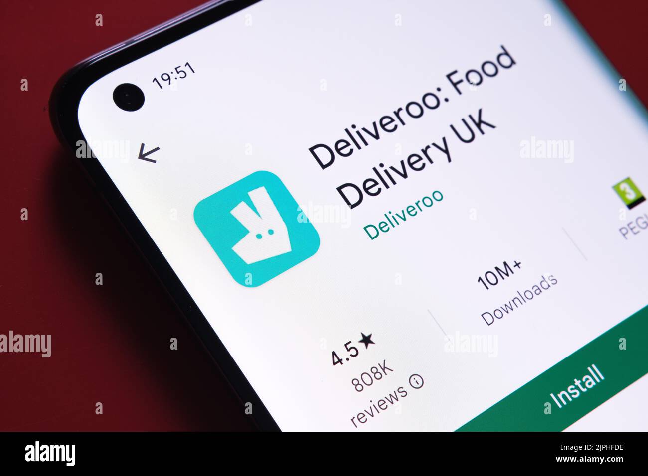 App deliveroo visualizzata in Google Play Store sullo schermo dello smartphone su sfondo rosso. Foto ravvicinata con messa a fuoco selettiva. Stafford, Regno Unito Foto Stock