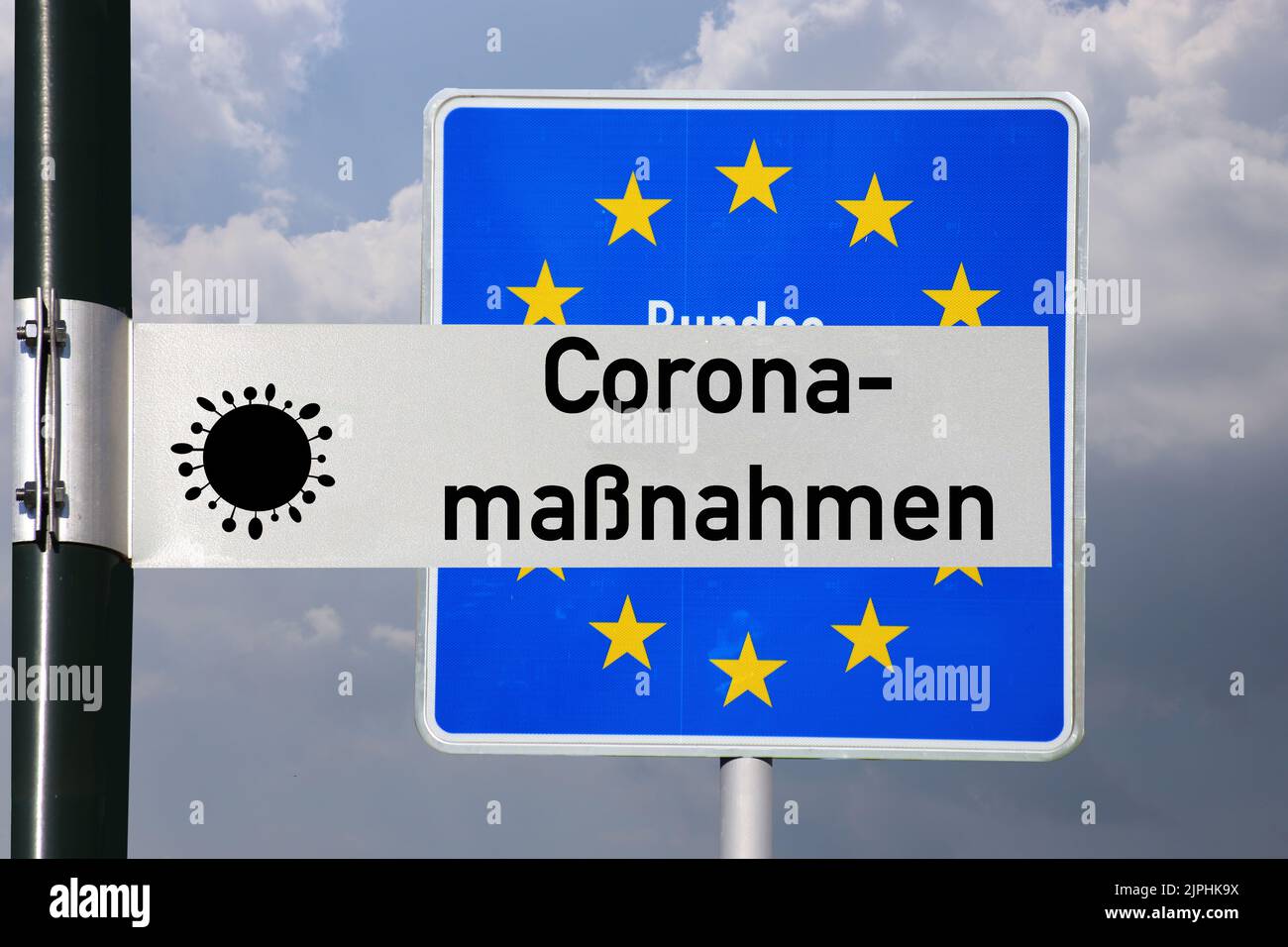 Symbolbild Coronamaßnahmen: Straßenschild mit der Aufschrift Coronamaßnahmen vor einem deutschen Grenzschild Foto Stock