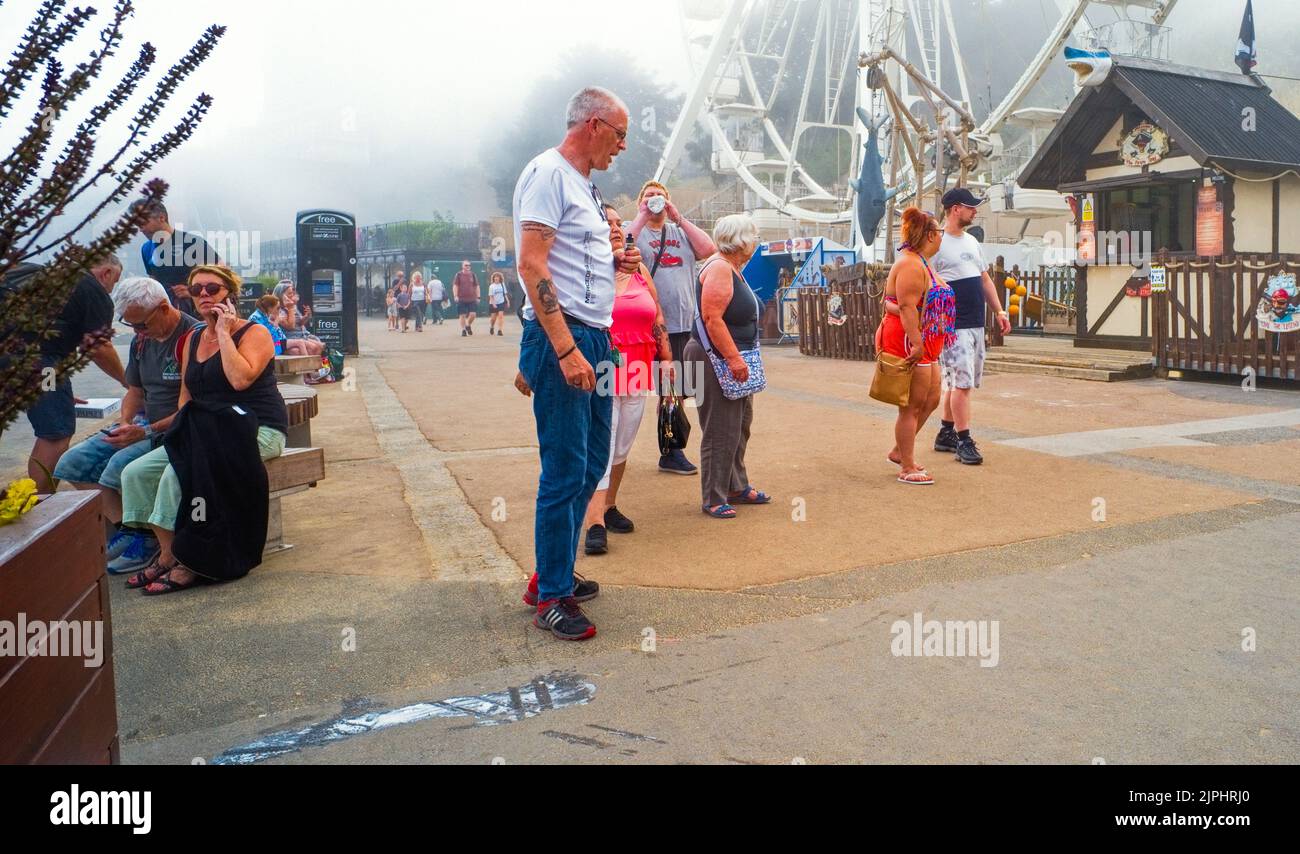 Persone in un gruppo di famiglia vicino alla grande ruota in una giornata di misty in estate a Scarborough, North Yorkshire Foto Stock
