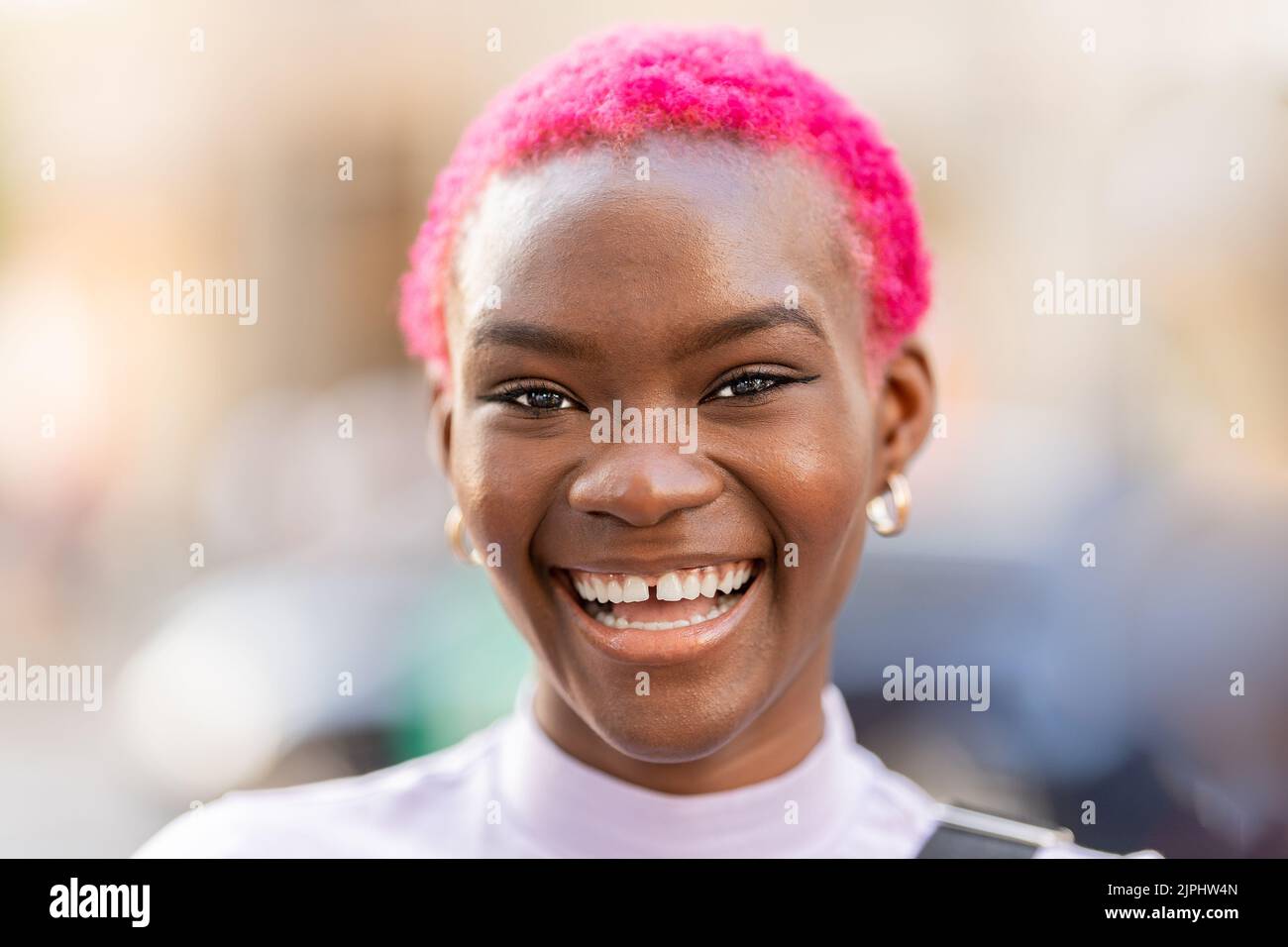 Donna africana con capelli corti rosa sorridente Foto Stock