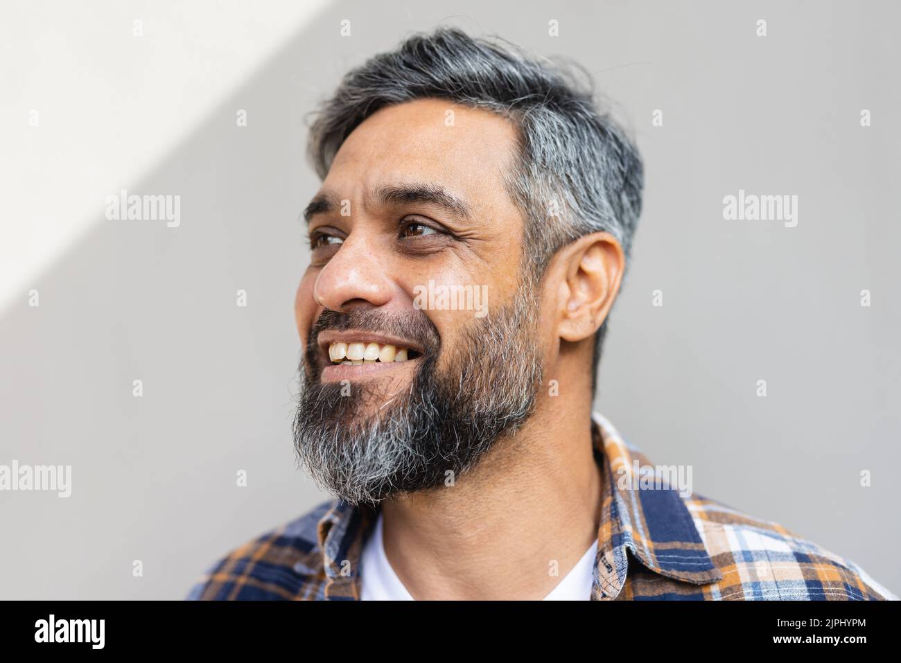 Felice uomo biraciale che indossa una camicia con maglietta bianca e sorridente Foto Stock