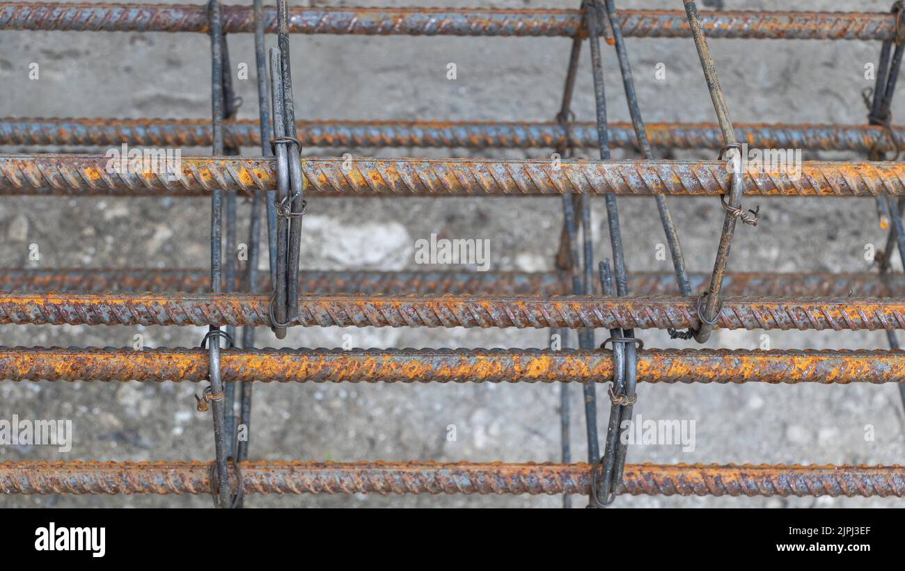Barre di rinforzo in metallo arrugginito in cantiere - dall'alto di barre metalliche solide resistenti agli agenti atmosferici per la fondazione di edifici in costruzione Foto Stock