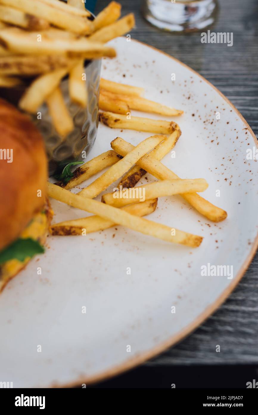 Patatine fritte e hamburger sul piatto all'aperto presso il ristorante Foto Stock