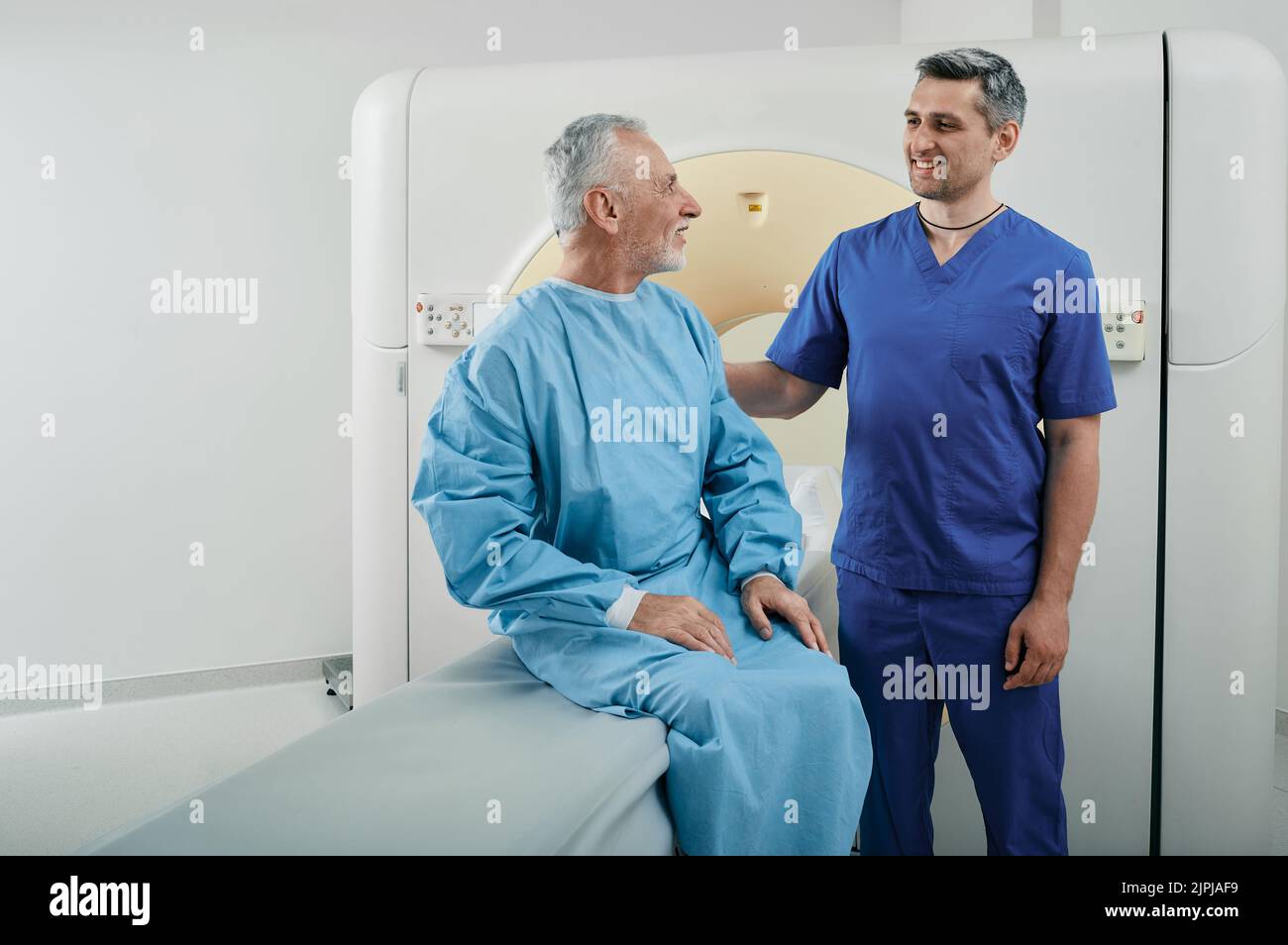 Tecnico di radiologia che parla con un paziente di sesso maschile nel reparto di radiologia dell'ospedale prima dell'esecuzione della scansione TC. Tomografia computerizzata Foto Stock