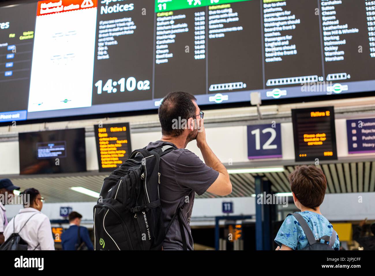 Uomo alla stazione Victoria che guarda il bordo di partenza Foto Stock