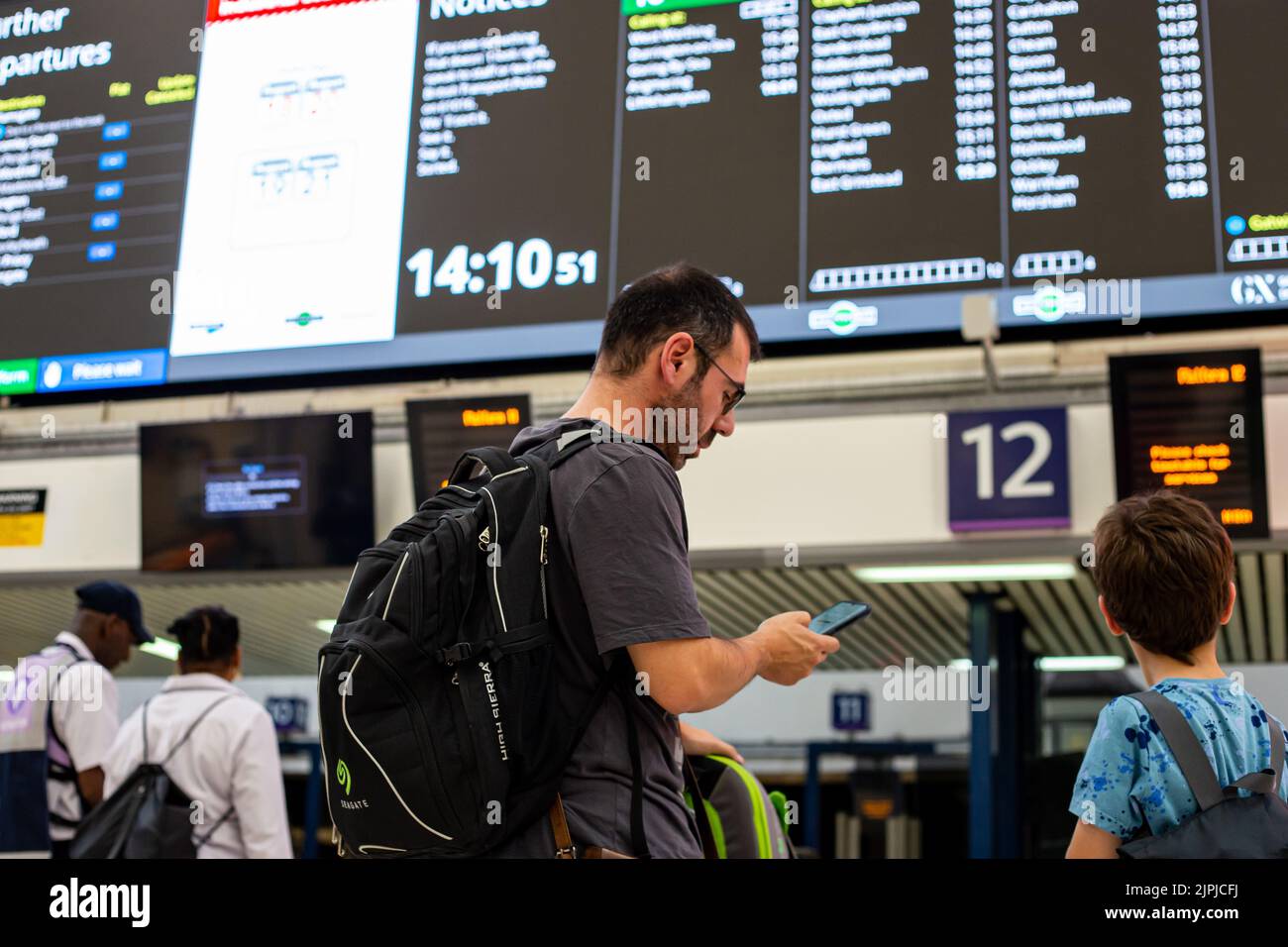 Uomo alla stazione Victoria che guarda il bordo di partenza Foto Stock