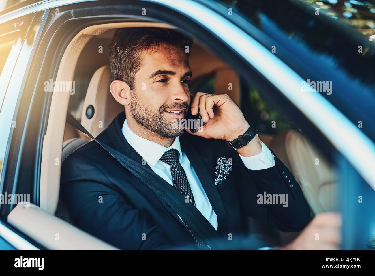 Il successo è garantito dalla comodità della sua auto. Un bel giovane uomo d'affari durante una chiamata mentre si è in viaggio. Foto Stock