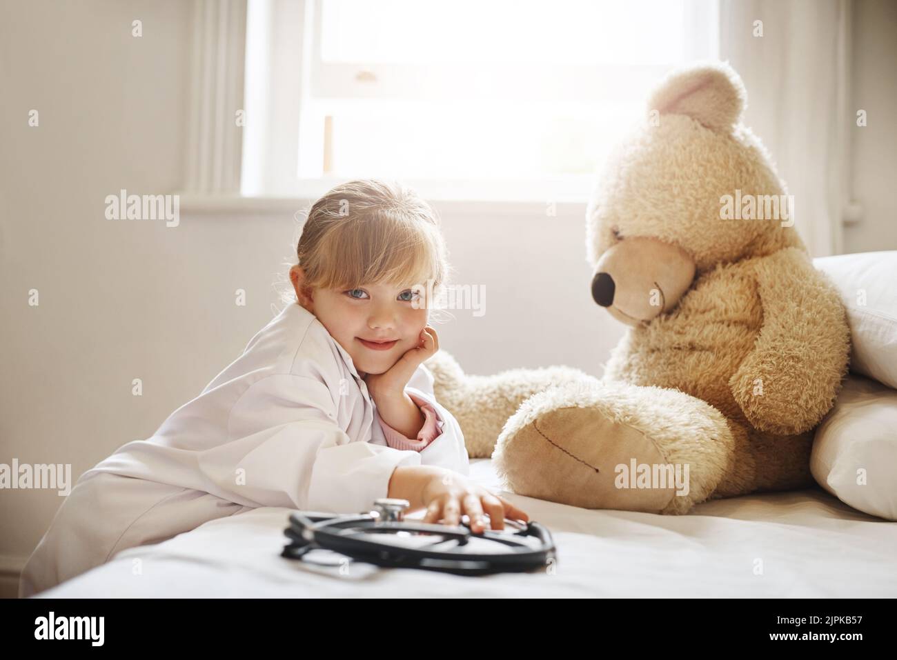 Solo un altro giorno di fare credere. Una ragazza adorabile vestita da medico e trattando il suo orsacchiotto come un paziente. Foto Stock