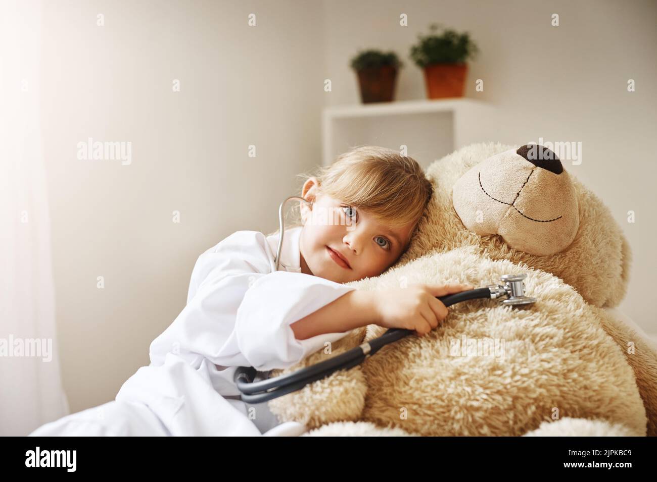 Teddy ha il cuore più grande Ive mai visto. Una bambina adorabile vestita come medico e trattando il suo orsacchiotto come paziente. Foto Stock