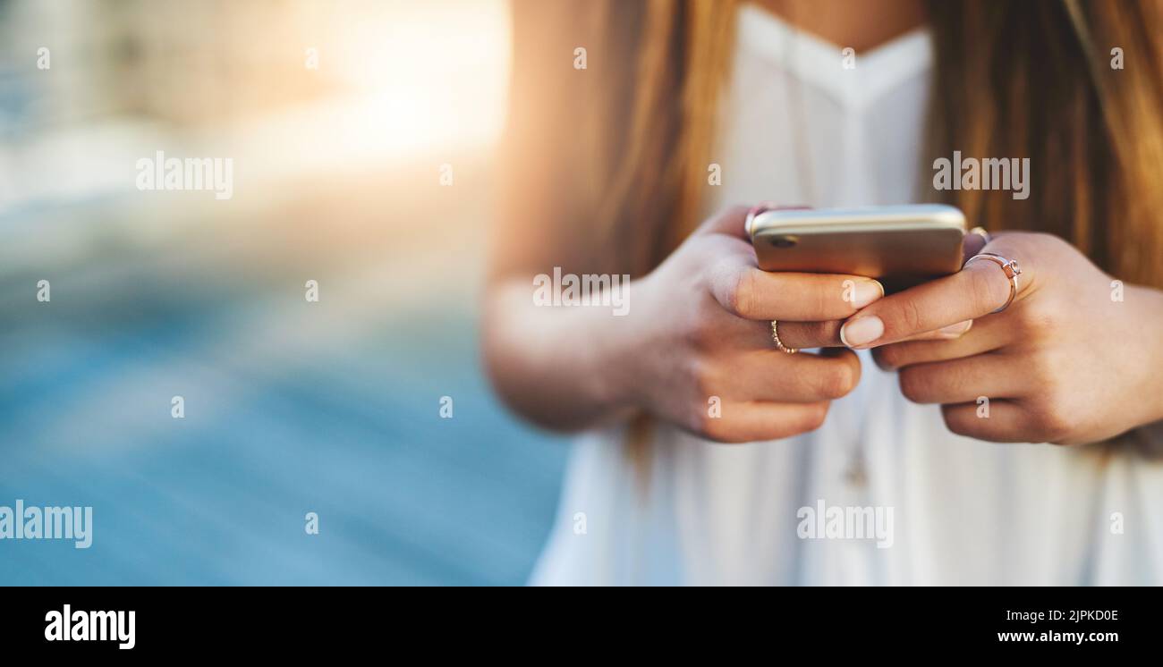 Social networking: Una giovane donna irriconoscibile che invia un messaggio di testo mentre si trova all'esterno. Foto Stock