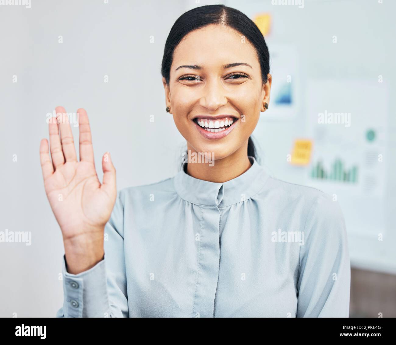 Donna che agita la mano per salutare mentre si presenta, sorridendo e gestendo durante la videochiamata via webcam in riunione virtuale in un ufficio. Ritratto di un Foto Stock