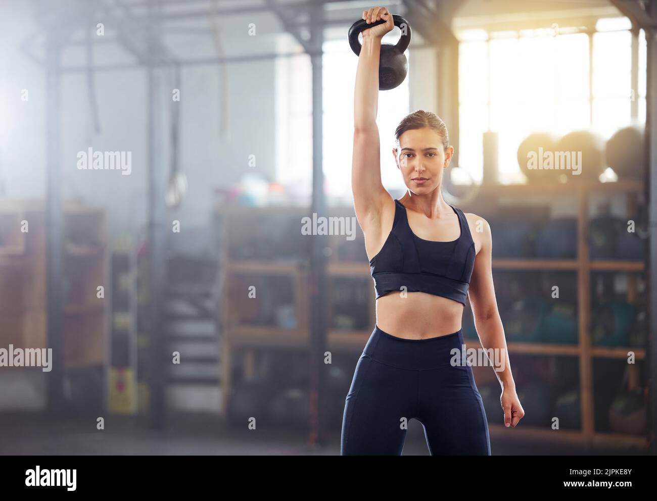 Donna forte e potente che fa esercizio di sollevamento pesi Kettlebell, allenamento o allenamento in palestra benessere. Persona sportiva che tiene o esercita con idoneità Foto Stock