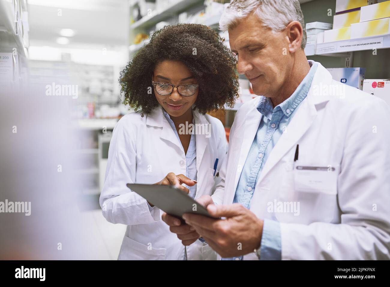 Dobbiamo tenere traccia di ciò che entra e esce: Due farmacisti si sono concentrati a camminare e a fare scorta all'interno di una farmacia. Foto Stock