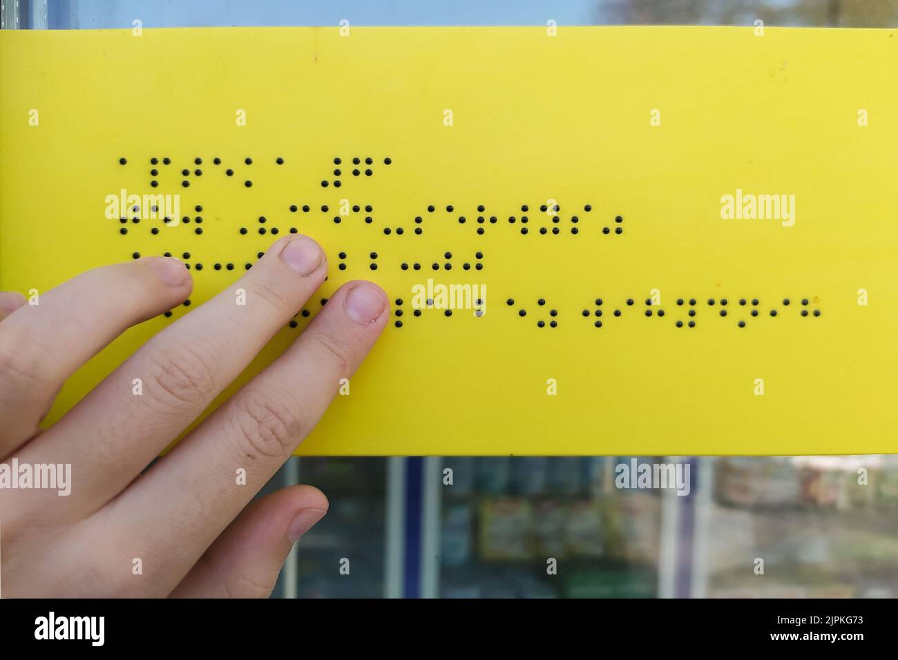 La mano della ragazza sta leggendo il testo braille all'aperto Foto Stock
