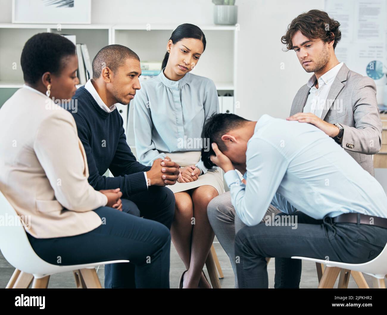 Depressione, sostegno e unità da parte dei colleghi che confortano maschio dopo aver ottenuto cattive notizie sul lavoro. Assistenza comunitaria da parte dei lavoratori seduti insieme, che sostengono Foto Stock