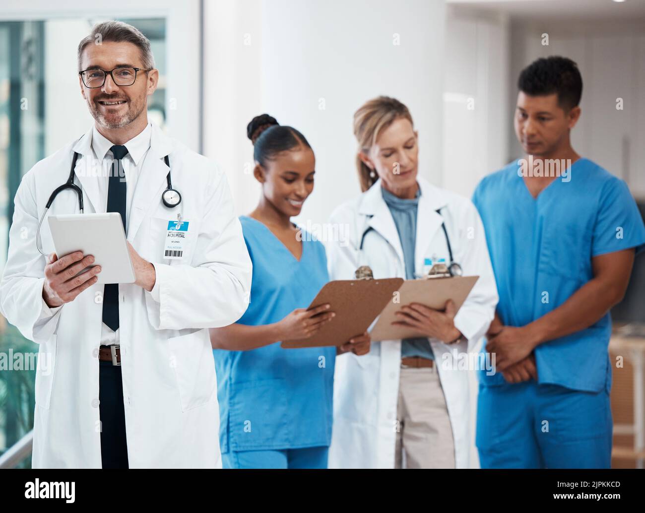 Ritratto di un leader felice in un gruppo di medici e infermieri che pianificano un intervento chirurgico in ospedale. Team medico o professionisti del settore sanitario che leggono Foto Stock