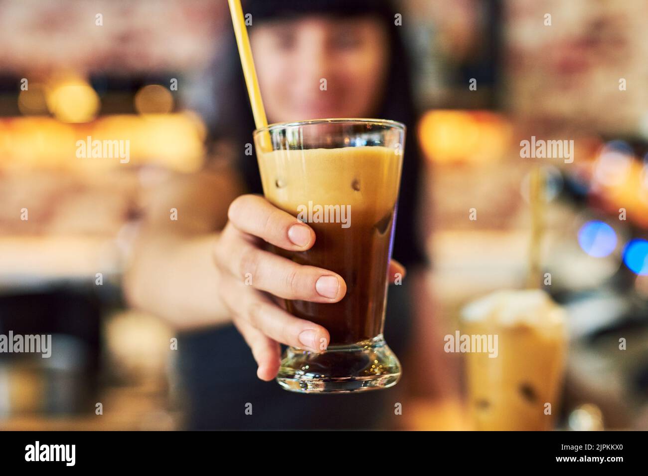 Serve bevande squisite, una cameriera giovane che lavora dietro il bancone in un bar. Foto Stock