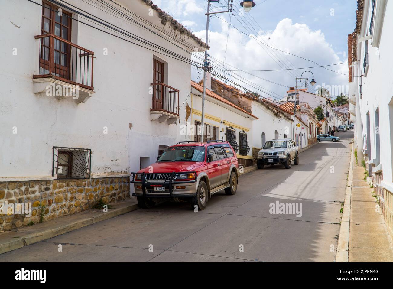 Una vista di una strada con parcheggio SUV e bellissimi edifici a Sucre, Bolivia Foto Stock