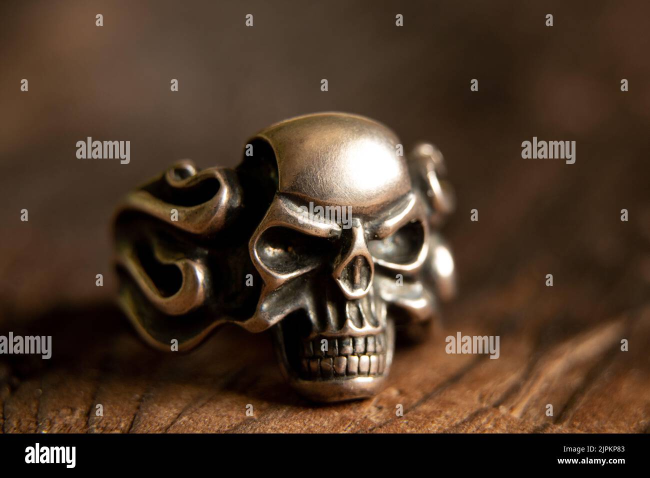 Anello d'argento con cranio su un tavolo di legno macro foto, morte e paura Foto Stock