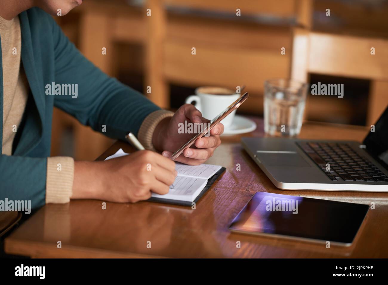 Mani di un uomo che controlla i messaggi nello smartphone e prende appunti Foto Stock