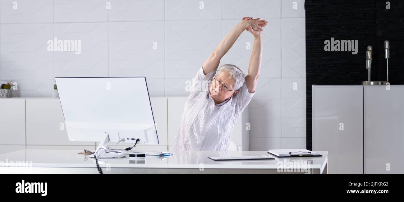 Buon lavoratore in ufficio che si allunga e si rilassa dietro il PC Foto Stock