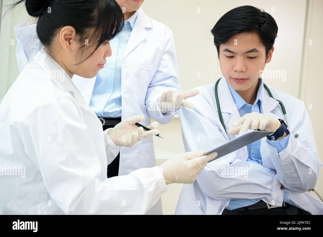 Giovani scienziati asiatici di sesso femminile e maschile condividono le loro idee di ricerca medica con il loro supervisore nel laboratorio. Un medico asiatico professionale maschile specialis Foto Stock
