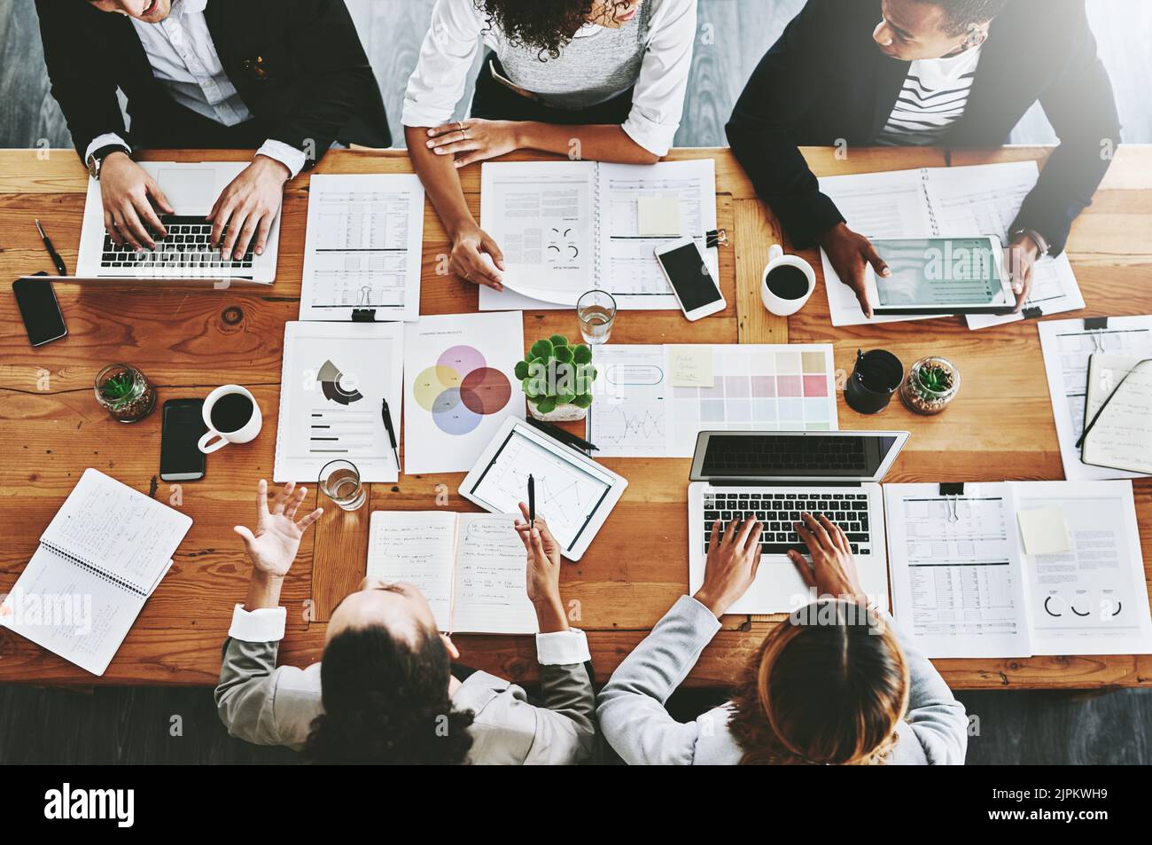 Overhead dei colleghi che hanno una riunione di marketing in un ufficio moderno. Al di sopra di un luogo di lavoro occupato, i colleghi si scambiano idee e sviluppano strategie per una startup Foto Stock