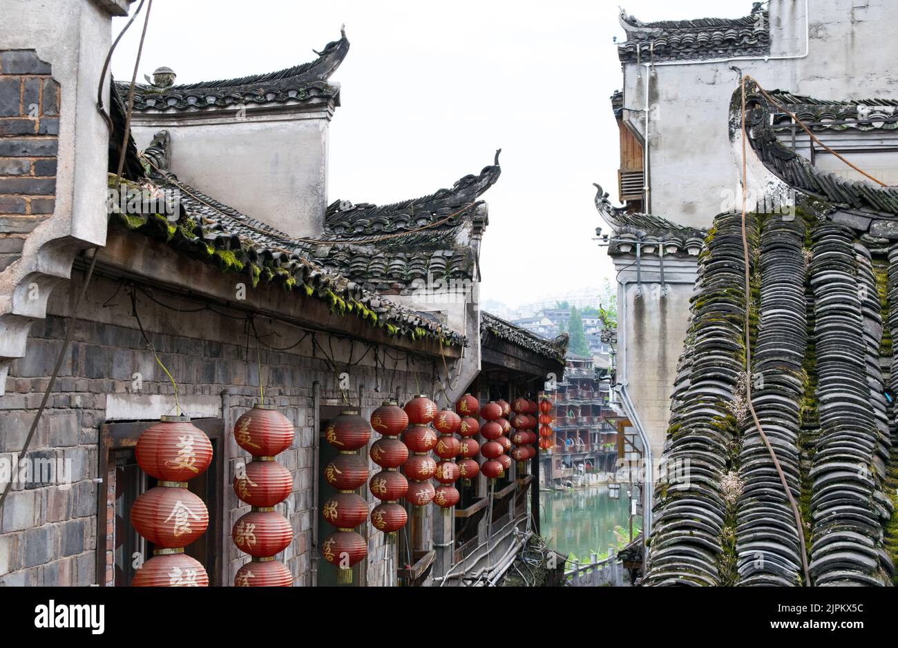 Tetti di stile Cinese decorati con lanterne rosse tradizionali Cinesi a Fenghuang. Foto Stock
