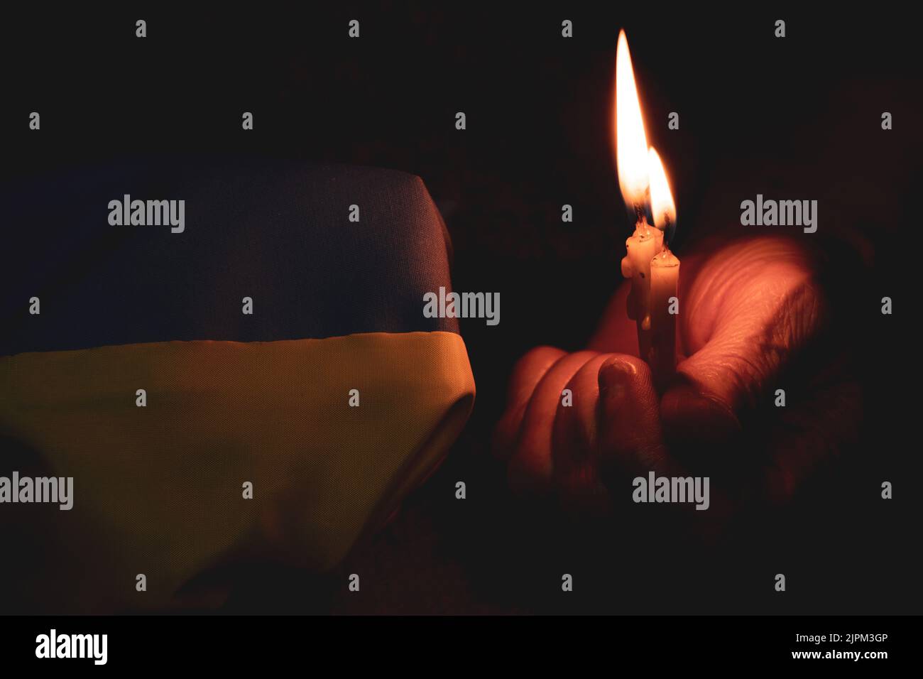 Nonna prega per l'Ucraina e detiene la bandiera dell'Ucraina e una candela, guerra in Ucraina, preghiera per il suo paese, nessuna guerra, pace per tutti. Fermare la guerra 2022 Foto Stock