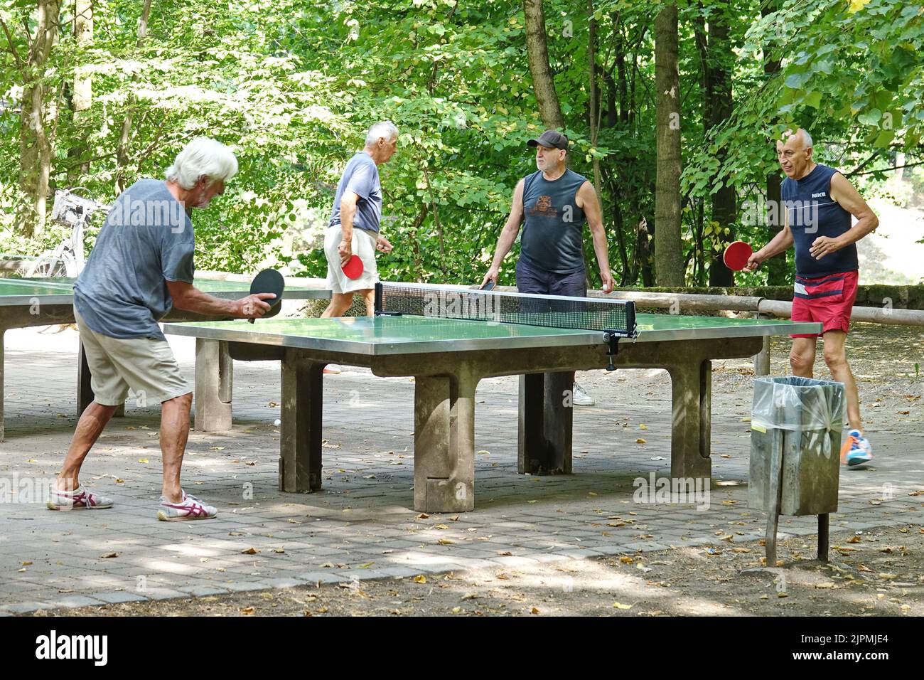 Gli anziani giocano a ping-pong nel parco. Soleggiato stile di vita all'aperto. Sport attivi. Monaco di Baviera, GERMANIA - Agosto 2022 Foto Stock