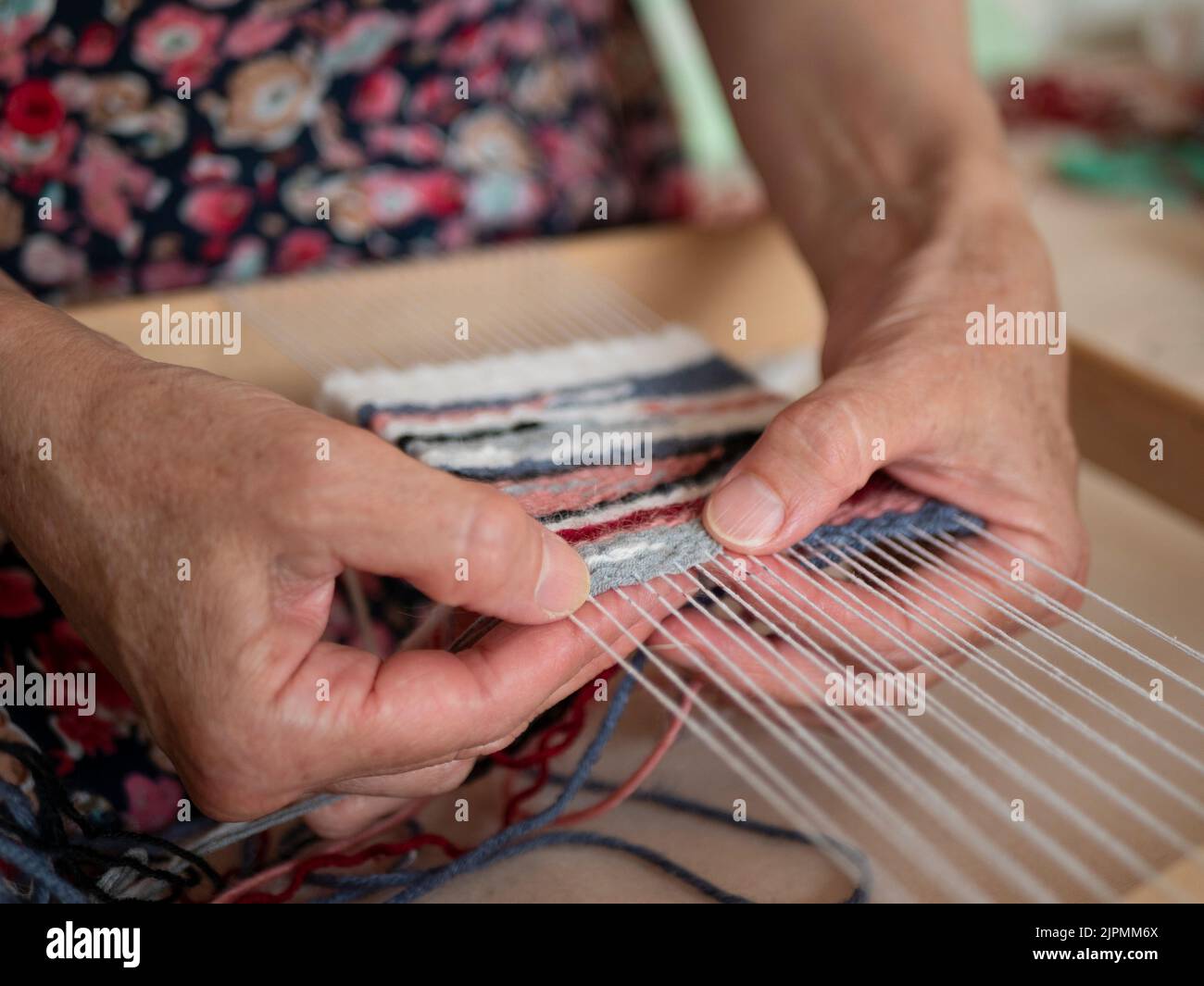 Tessitore artigianale è al lavoro sul telaio della mano. Tessitura di arazzi, fuoco selettivo. Processo di lavorazione dell'artigiano Foto Stock