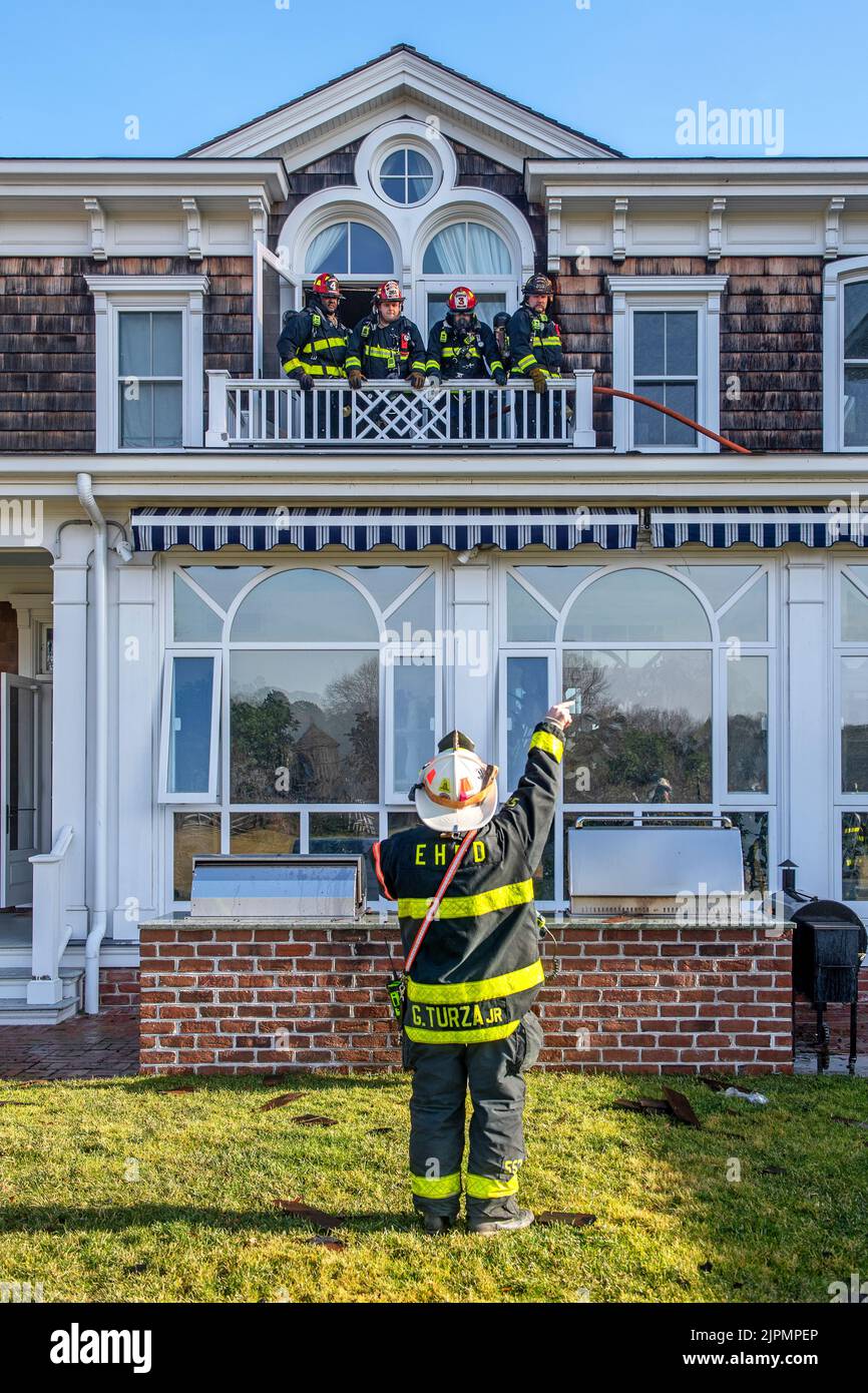 Gerard Turza, Jr., Capo del Dipartimento dei vigili del fuoco di East Hampton, emette ordini ai suoi vigili del fuoco in piedi su un balcone al secondo piano come il Bridgehampton Fire De Foto Stock