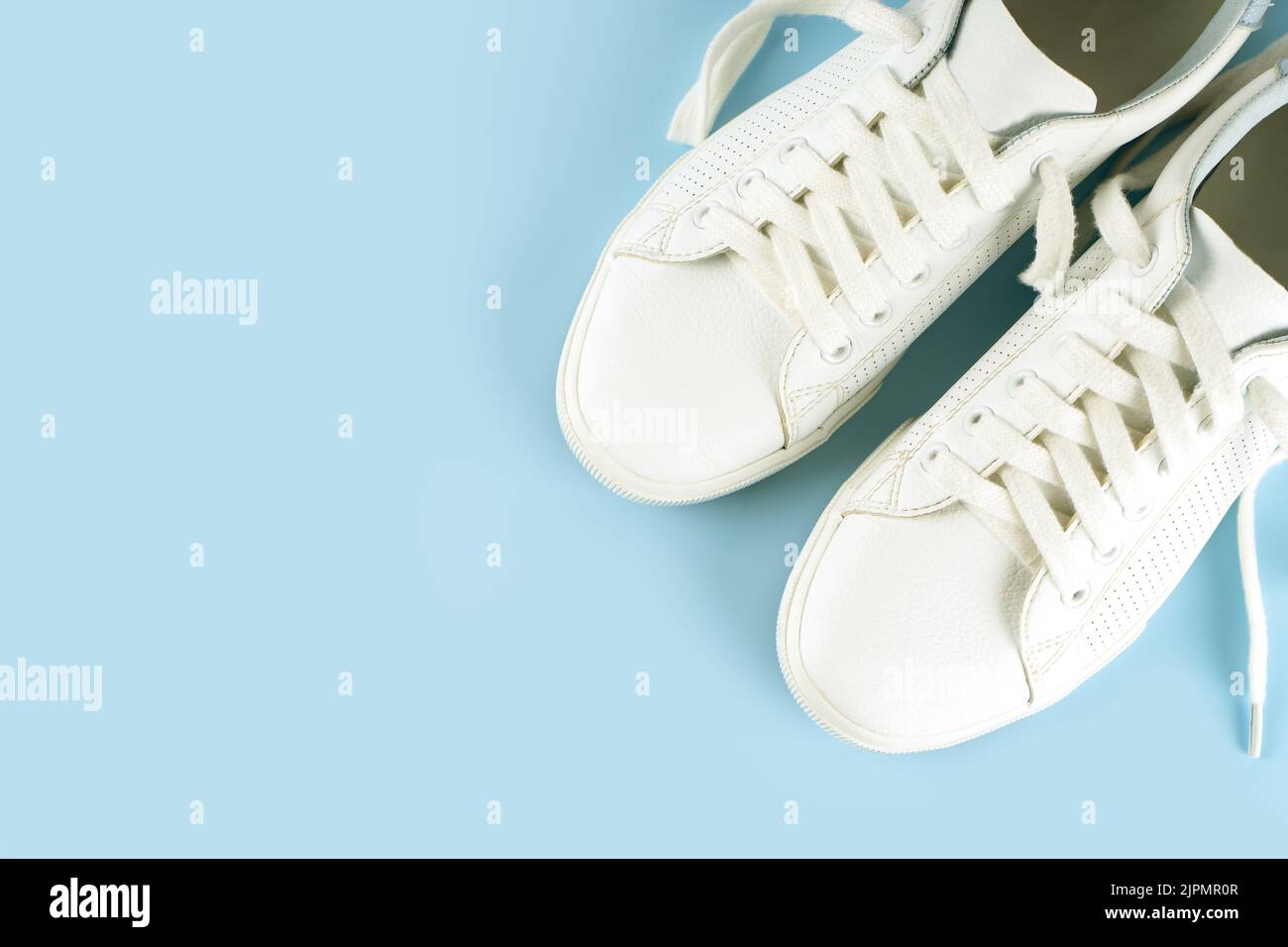 Paio di sneaker bianche su sfondo blu. Scarpe UNISEX, sneaker bianche eleganti. Vista dall'alto, disposizione piatta, mockup con spazio di copia per il testo Foto Stock