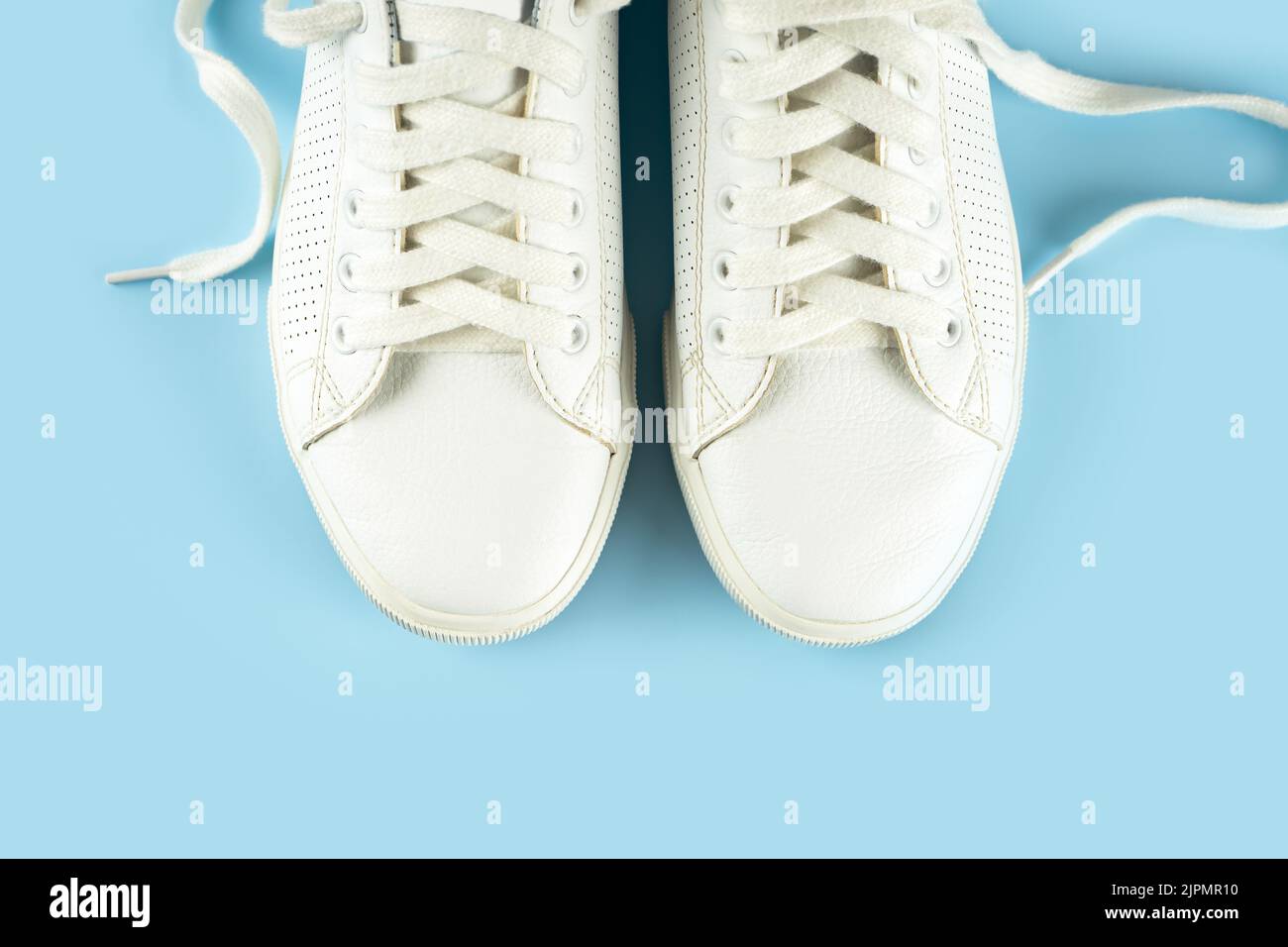 Paio di sneaker bianche su sfondo blu. Scarpe UNISEX, sneaker bianche eleganti. Vista dall'alto, disposizione piatta, mockup con spazio di copia per il testo Foto Stock