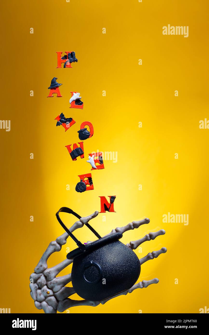 La parola Halloween ortografia in lettere colorate in volo su uno sfondo giallo Foto Stock