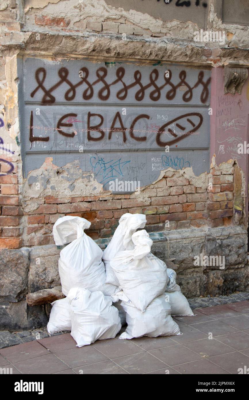Belgrado-Serbia - 15 giugno 2022: Dettaglio di vecchia casa in rovina con graffiti 'pane' su una parete di facciata e costruttori sacchi di spazzatura sfuso Foto Stock
