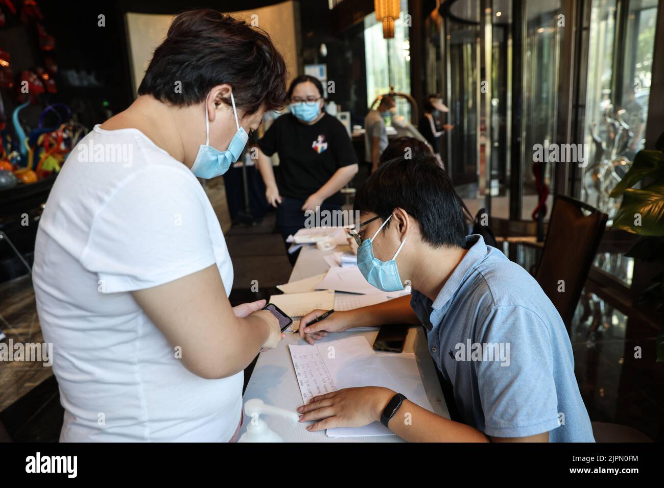 (220819) -- HAIKOU, 19 agosto 2022 (Xinhua) -- Un membro del team di servizio aiuta un turista bloccato registrare le informazioni di volo in un hotel in Haikou, Cina del sud provincia di Hainan, 14 agosto 2022. Hainan continua i suoi sforzi per facilitare il ritorno dei turisti bloccati nella provincia durante l'ultima ripresa del COVID-19. Le autorità locali hanno organizzato un team di assistenza speciale, aiutando i turisti in difficoltà a tornare alle loro case in tempo. (Xinhua/Zhang Liyun) Foto Stock