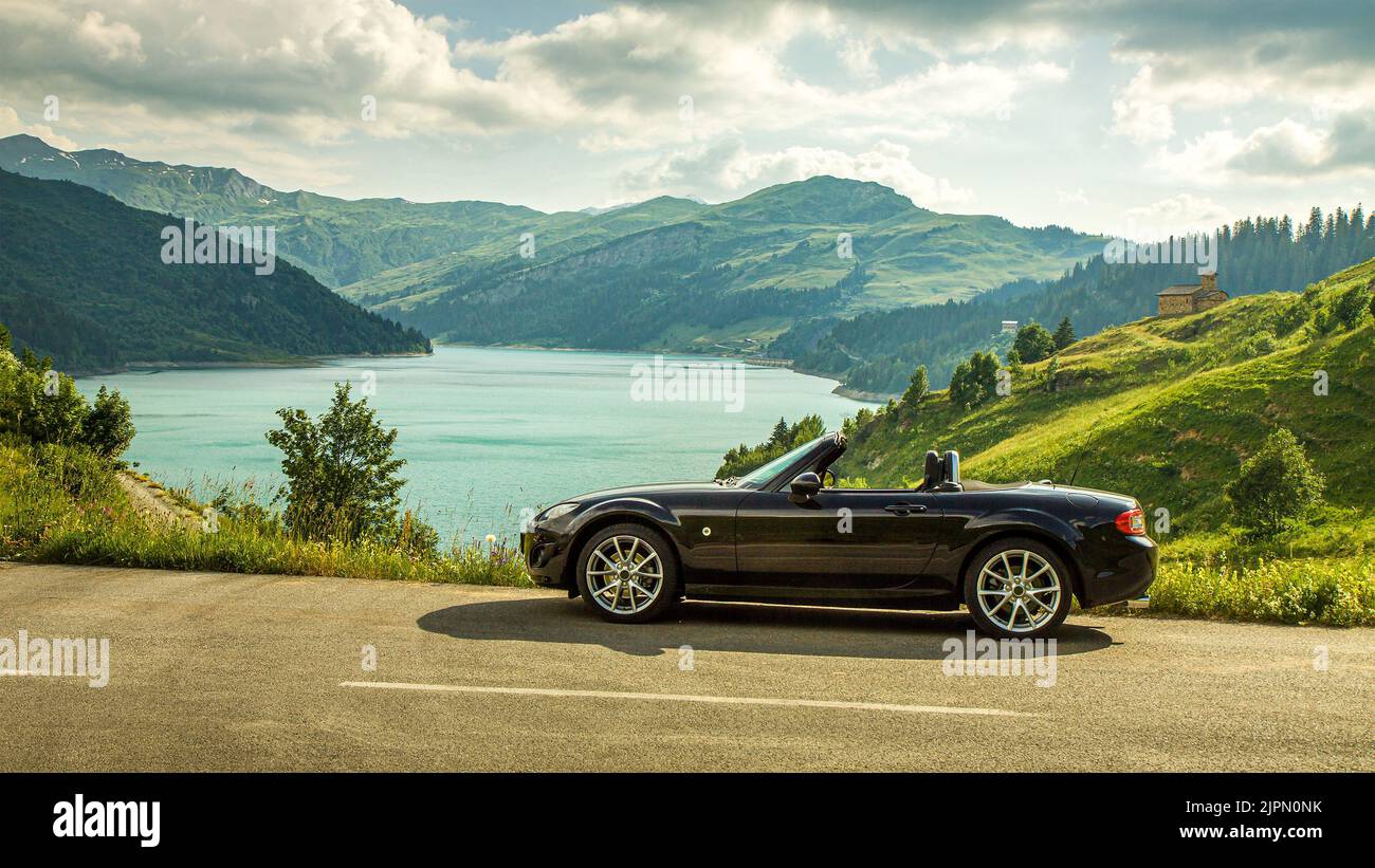 Beaufort, Francie - 02 luglio 2018. Auto sportiva - roadster Mazda MX-5 NC, NC2, NCFL, Miata su strada alpina. Lago di Roselend nella valle Beaufortain, S Foto Stock